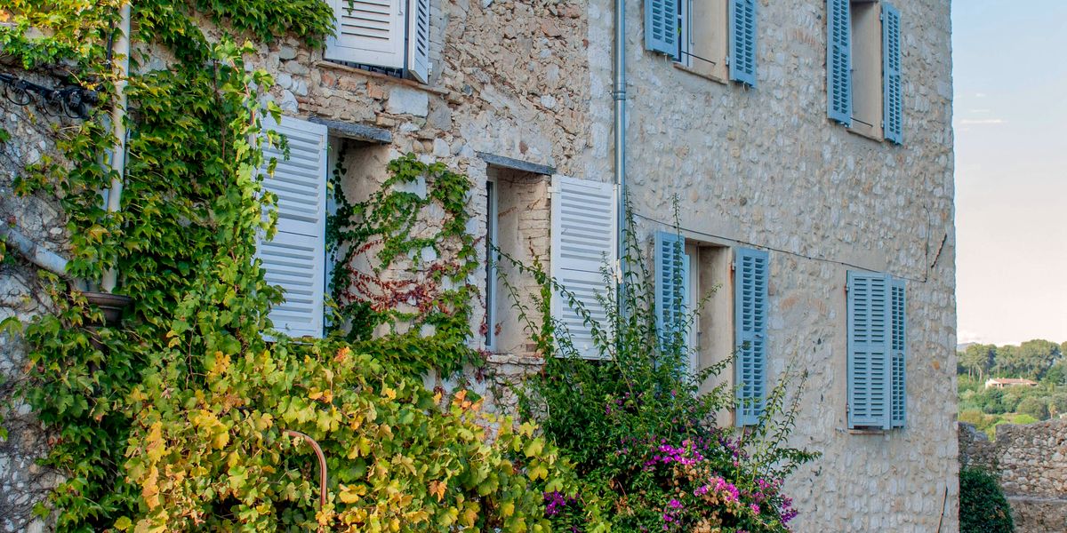 A sun-baked village square in the South-West, shutters closed against the afternoon heat